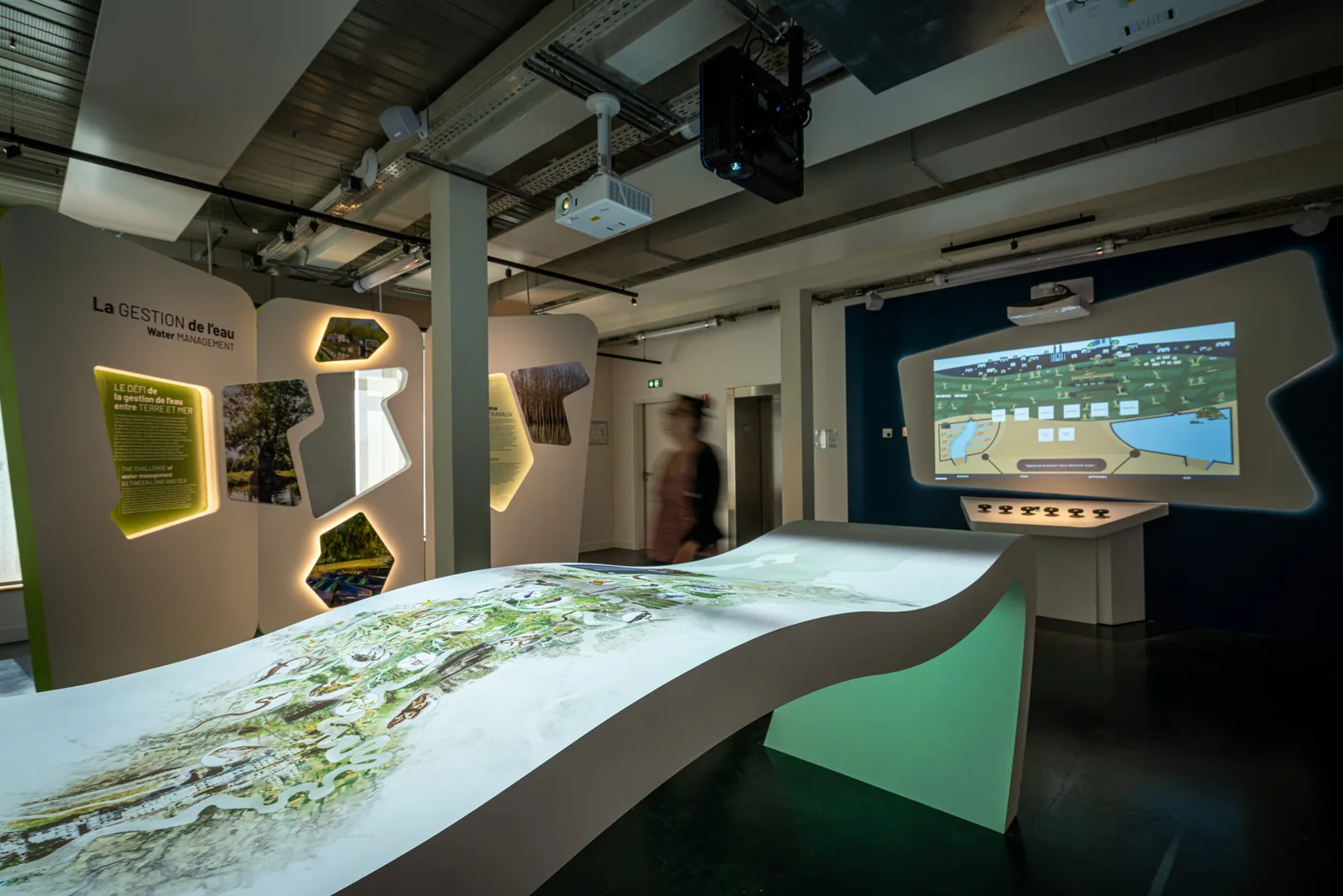 Espace d'exposition moderne avec installations interactives et éclairage dramatique mettant en valeur les œuvres.